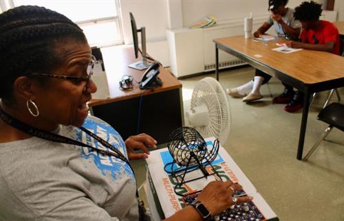 woman calling numbers for bingo game and two people looking at bingo card